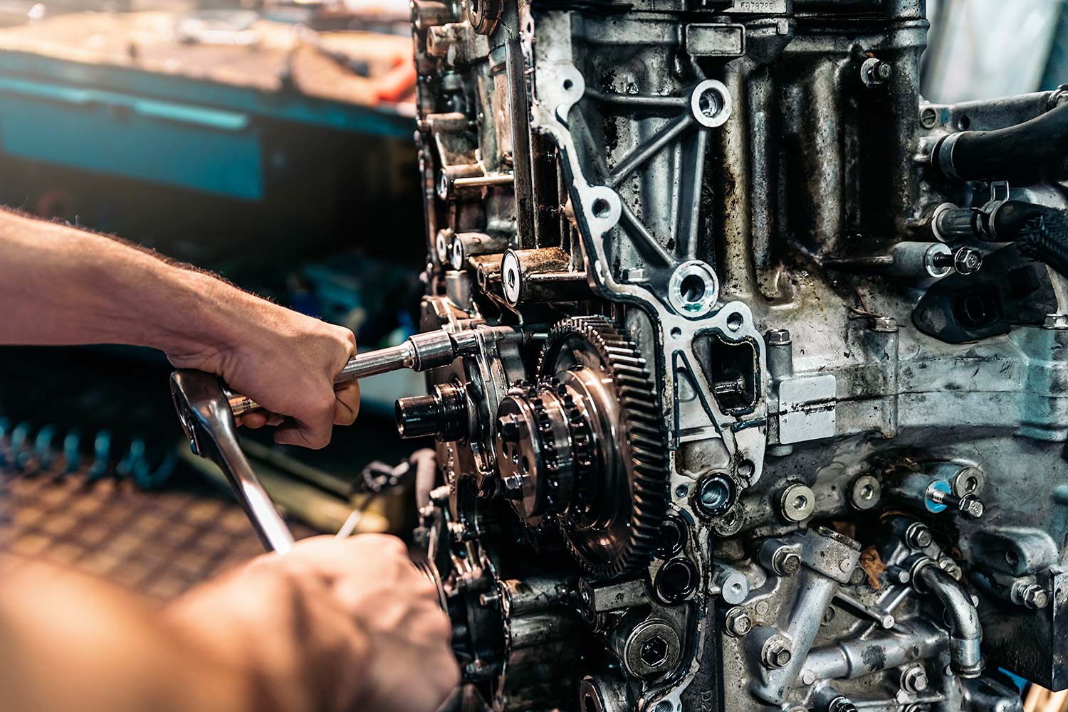 Mechanic using hand tools on an exposed engine assembly.
